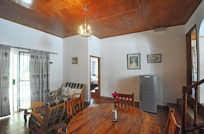 Un comedor con una mesa de madera, sillas, una araña y un refrigerador.