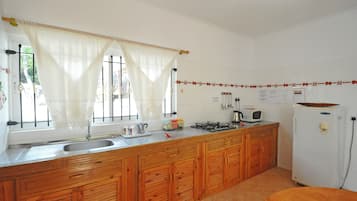 Une cuisine avec des armoires en bois, un évier, une cuisinière, un four à micro-ondes et un réfrigérateur.