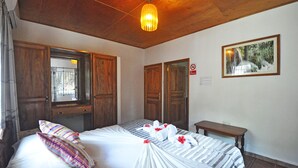 A hotel room with wooden furniture, a bed with white bedding, a bench, and a painting on the wall. - Acquario Villa (Praslin Island)