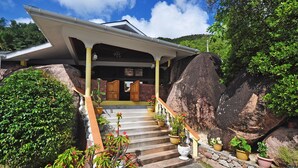 A house with a covered porch, stone steps, and potted plants. - Acquario Villa (Praslin Island)