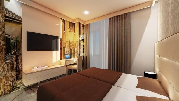 A modern hotel room with a large bed, a desk with a laptop, a TV, and a wall-mounted shelf. - Hotel Old Town (Sarajevo)
