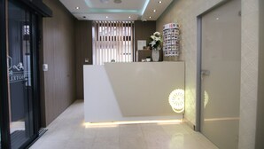 A hotel reception area with a modern design, featuring a reception desk, a decorative wall, and a visible door. - Hotel Old Town (Sarajevo)