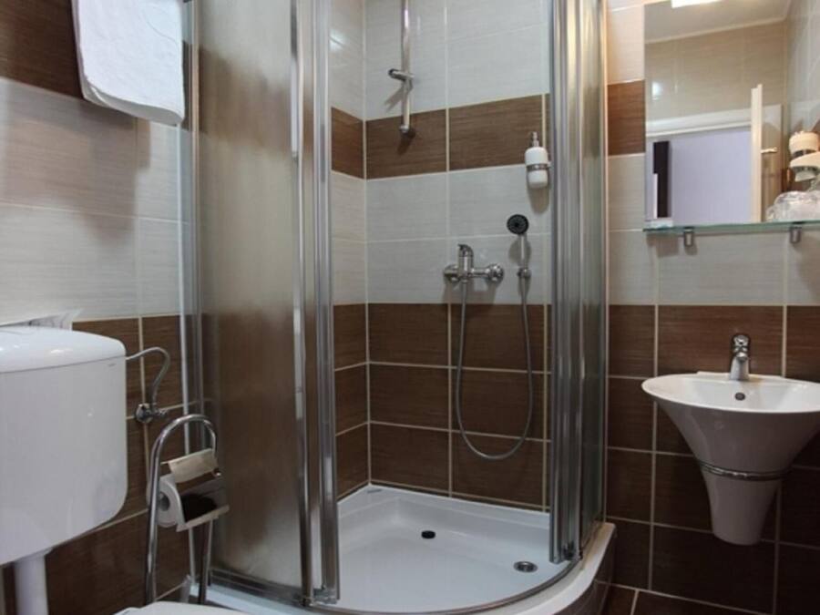 A modern bathroom with a glass-enclosed shower, a toilet, and a sink.