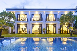 A modern multi-story hotel with a swimming pool in front. - Hoi An Hideaway Villa (Da Nang)