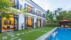 A two-story house with a swimming pool, a well-maintained lawn, and a balcony with outdoor furniture. - Hoi An Hideaway Villa (Da Nang)