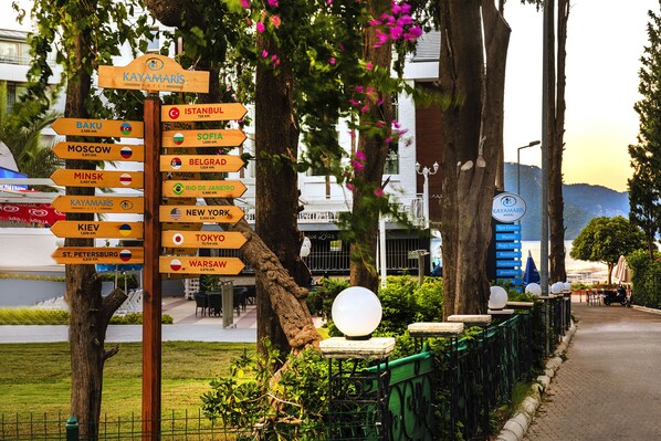 Un posteñal de madera con flechas indicando diferentes ciudades y el nombre de un hotel.