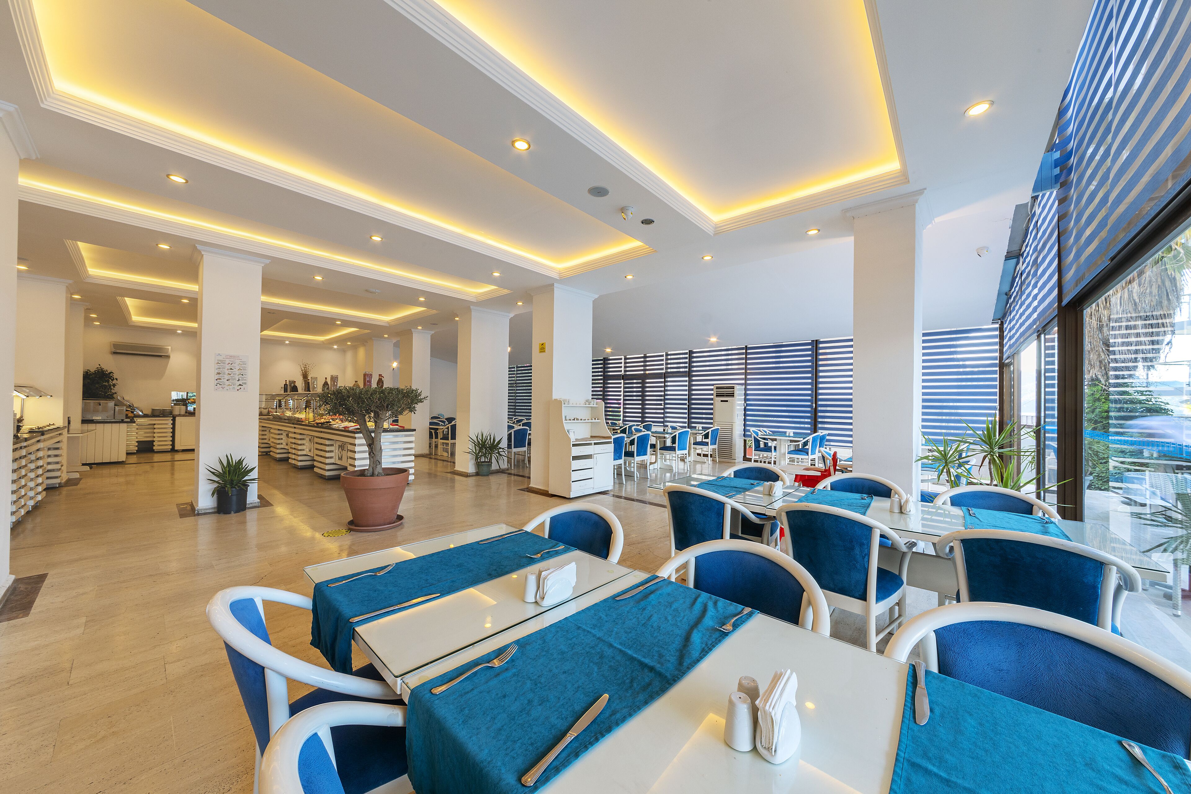 A modern restaurant with blue and white decor, featuring tables with blue tablecloths, white chairs, and a bright, well-lit interior.