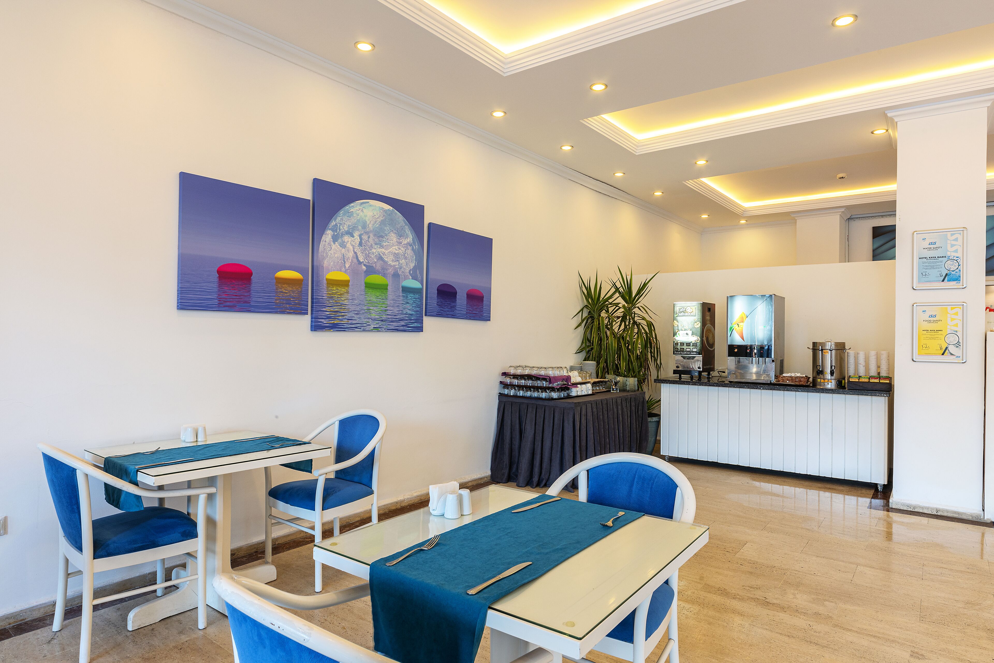 A hotel lobby with a reception desk, seating area with tables and chairs, and artwork on the walls.
