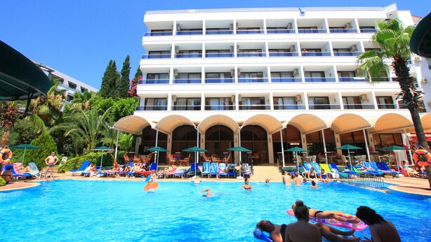 Un hotel con piscina rodeada de sillones de descanso y sombrillas.