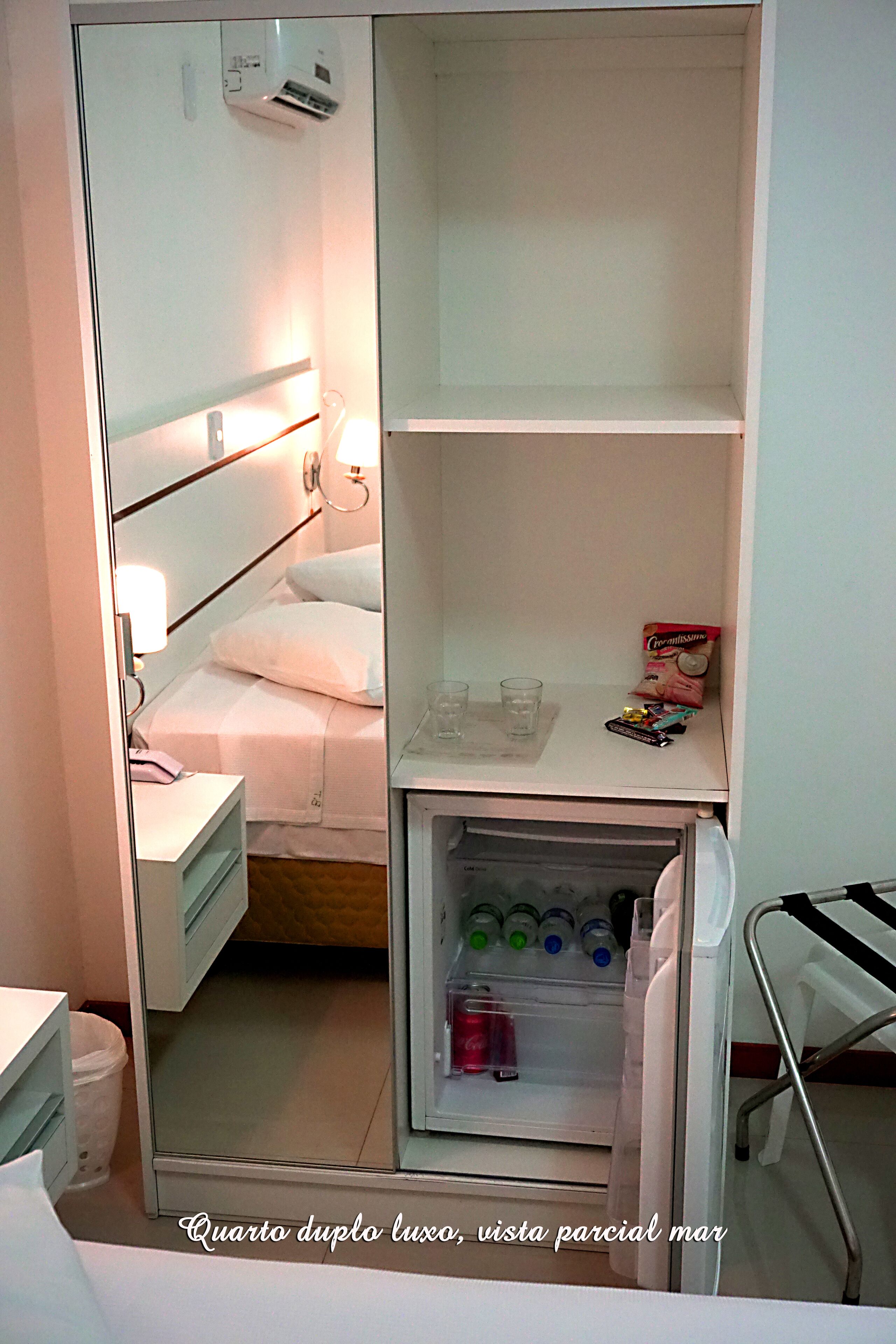 Une chambre d’hôtel de taille réduite, comprenant un lit, une table de chevet et un mini-bar.