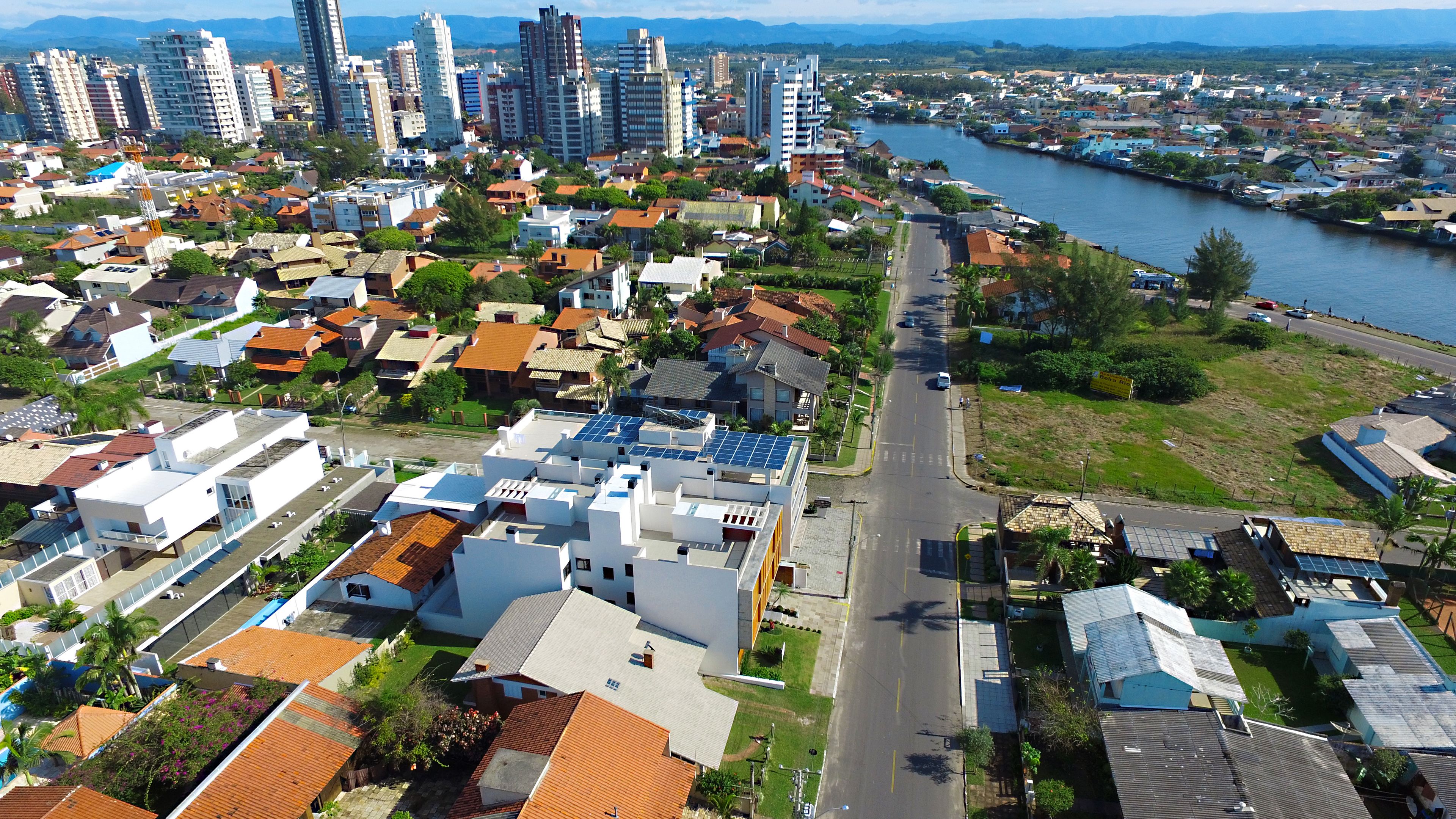 An aerial view of a residential area with modern and traditional houses, a river, and a road.