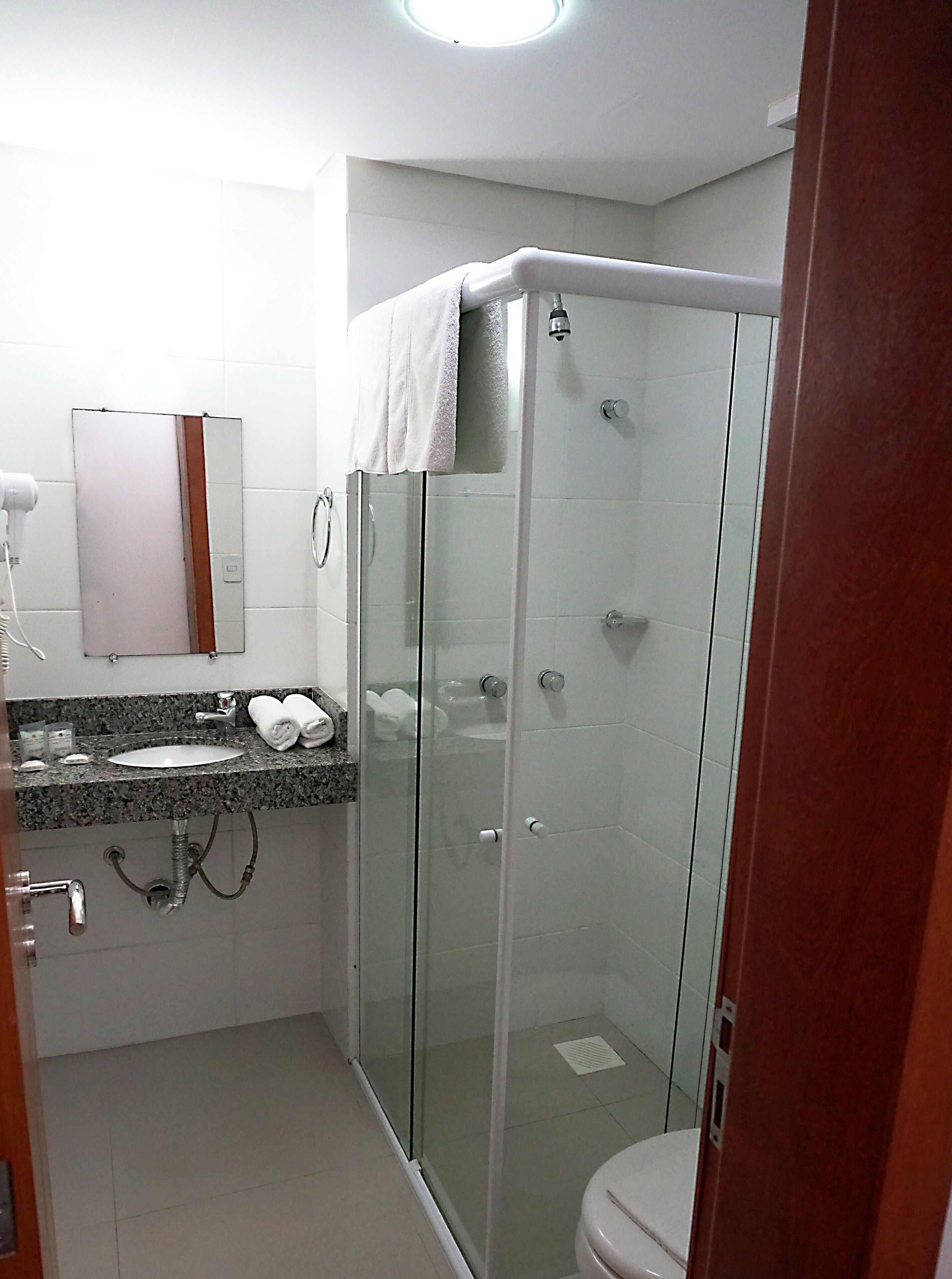 A modern bathroom with a glass-enclosed shower, a sink with a marble countertop, and a mirror above the sink.