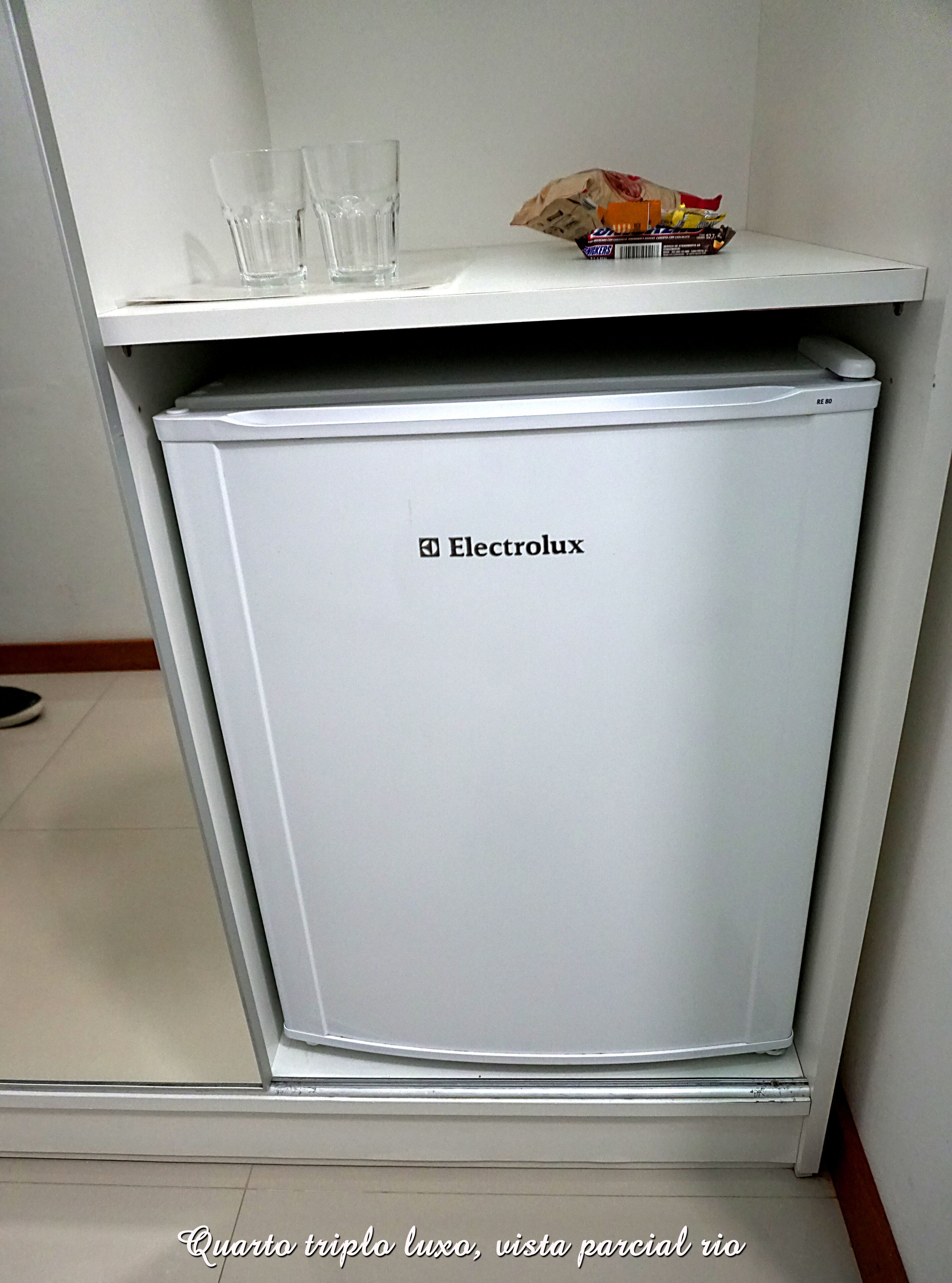Un refrigerador blanco Electrolux compacto en una kitchenette, con dos vasos en el estante superior.