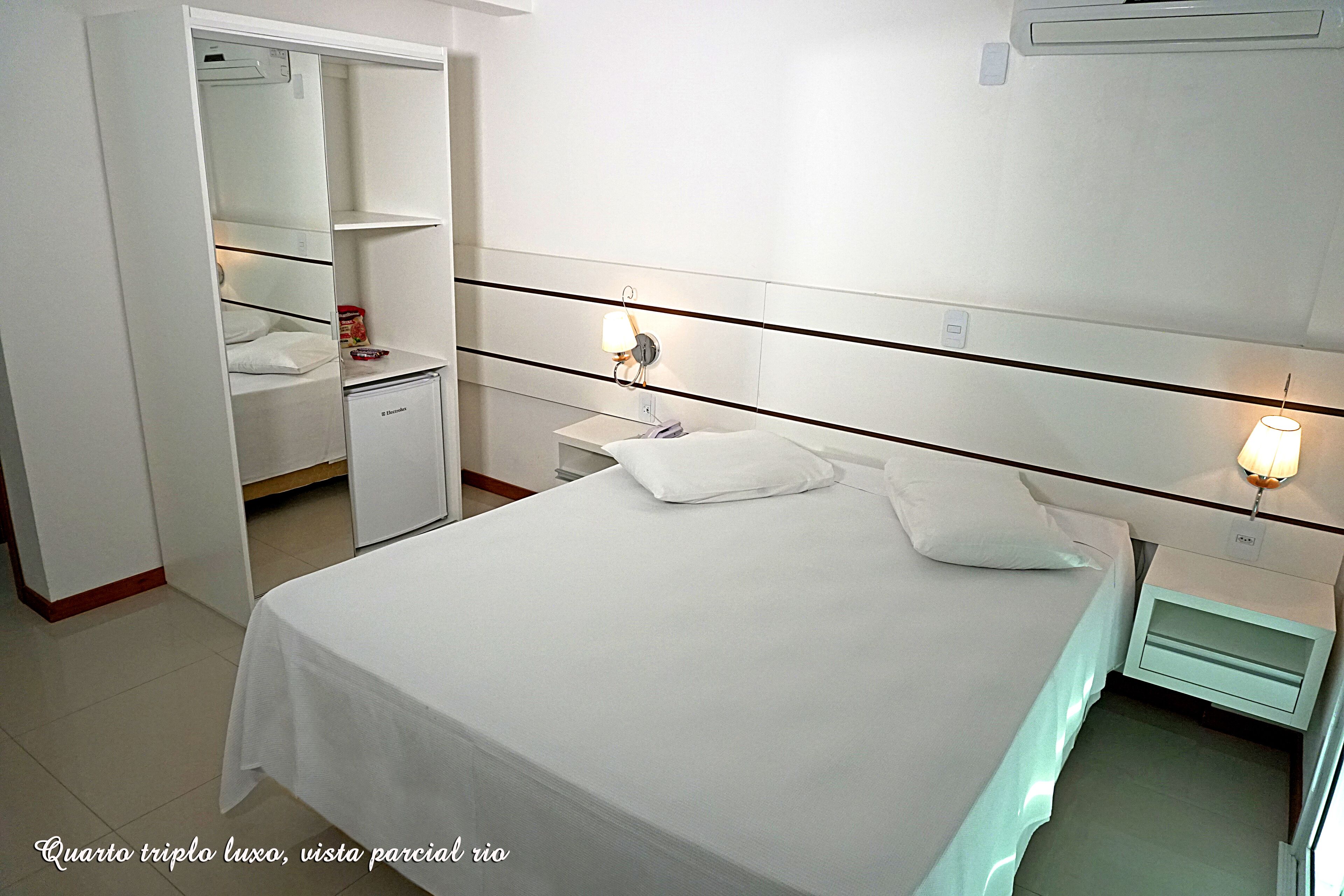 A hotel room with a large bed, a wardrobe, a bedside table, and a nightstand.