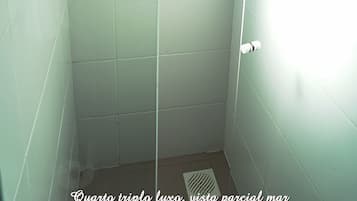 Un baño con azulejos blancos, ducha y ventana con una toalla colgada.