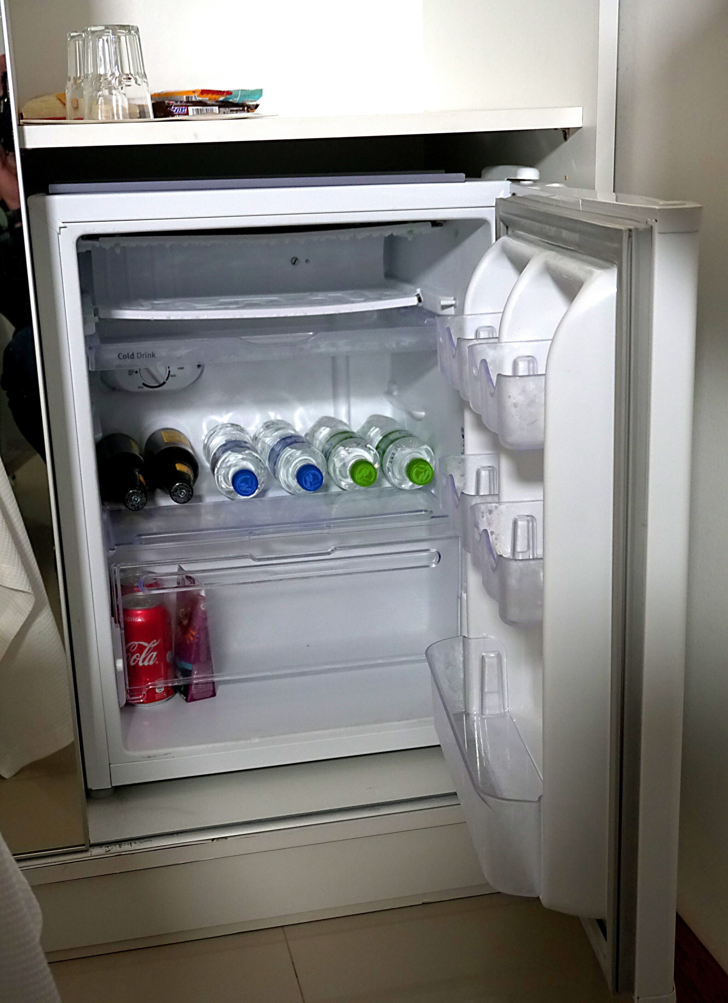 A refrigerator with multiple shelves containing various beverages and a Coca-Cola can.