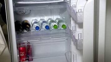 A refrigerator with multiple shelves containing various beverages and a Coca-Cola can.