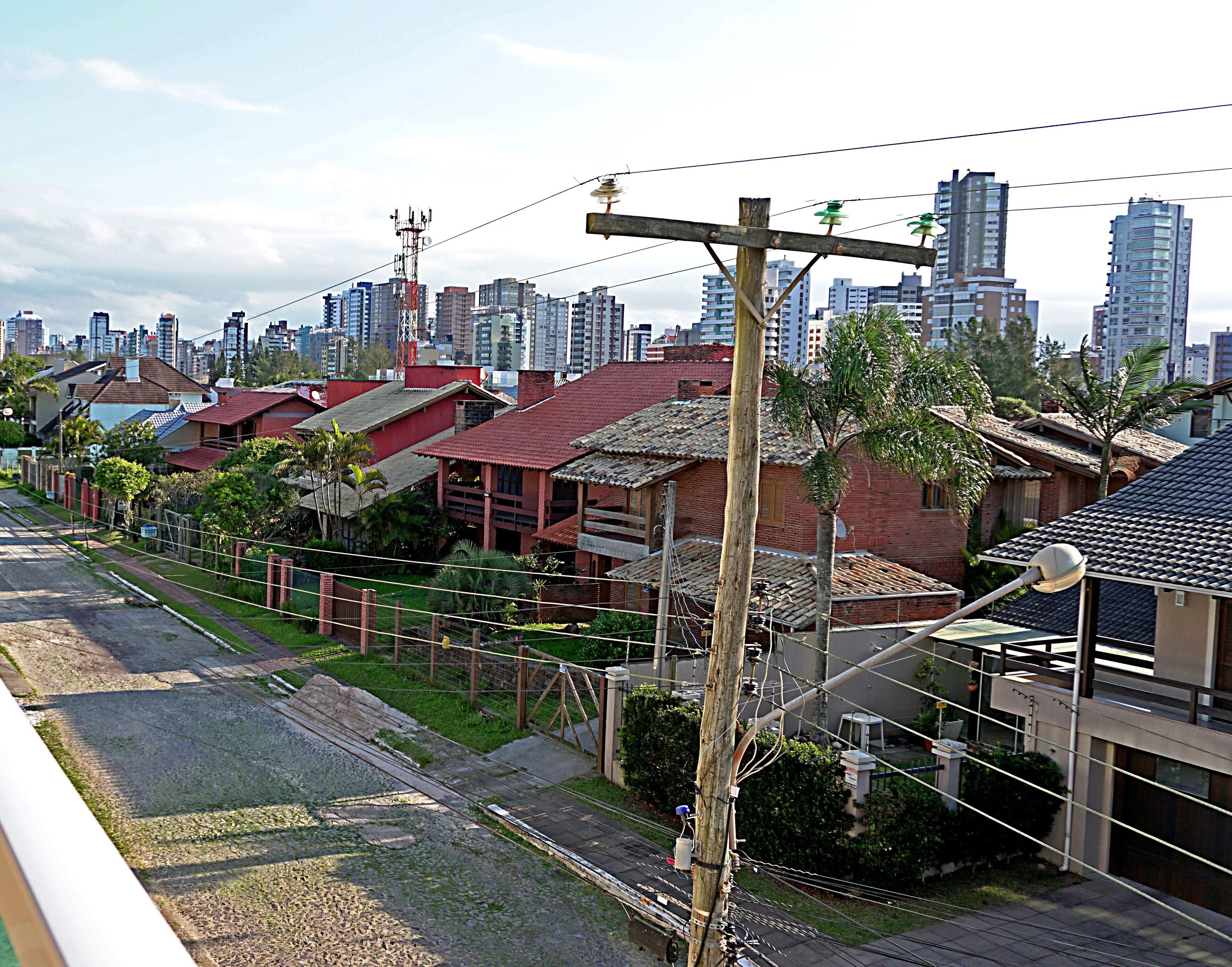 Zona residencial com mistura de edifícios tradicionais e modernos, céu claro e uma linha férrea.