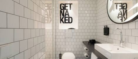 A modern bathroom with white tiles, a white toilet, a sink, and a mirror.