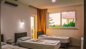 Habitación de hotel con dos camas, una ventana con vistas, una mesita de noche con lámpara y un equipo de aire acondicionado.