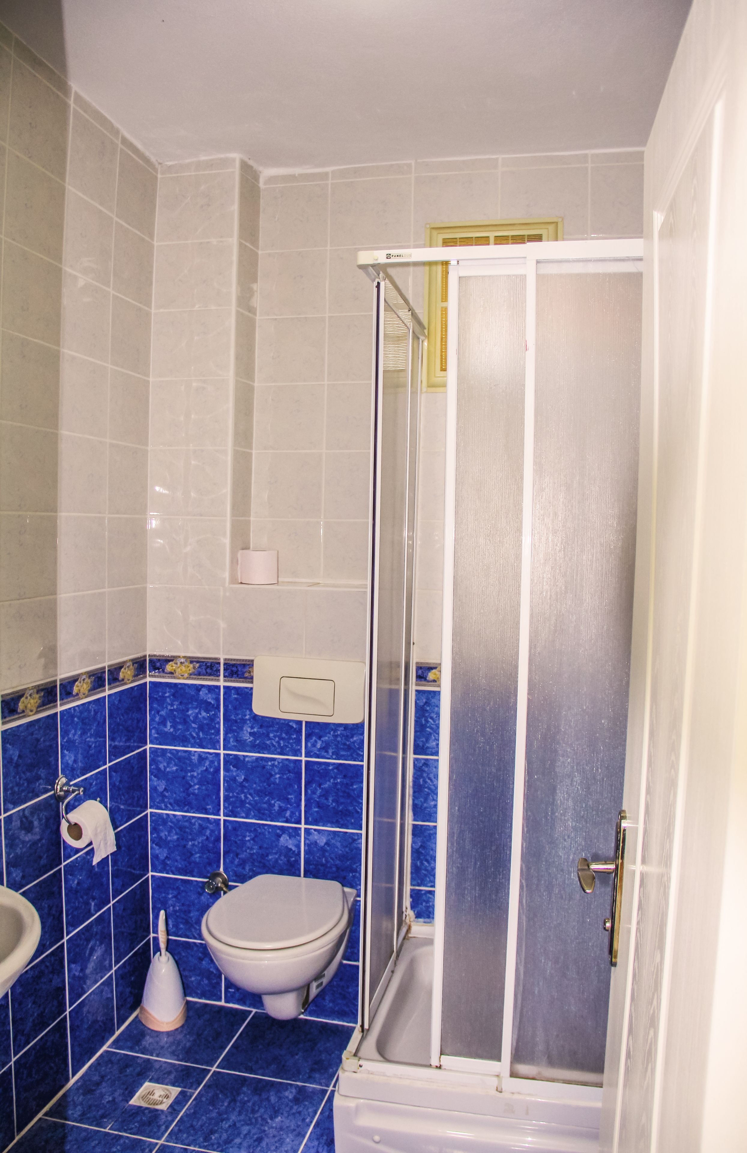 A bathroom with a shower enclosure, a toilet, and a sink.