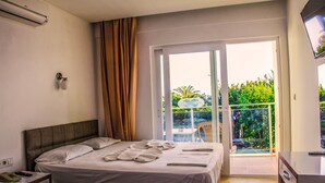 Habitación de hotel con dos camas, un balcón con vistas a zonas verdes y un televisor a la derecha.