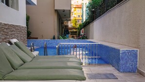 Un área de piscina con sillones de descanso y una piscina con baldosas.