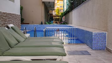 Una piscina al aire libre, sombrillas, sillones reclinables de piscina