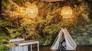 Una habitación con una tienda de campaña, una mesa y un mural en la pared que representa un bosque.