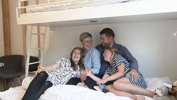 Een stapelbed met vier personen erop, een stoel en een kleine tafel.