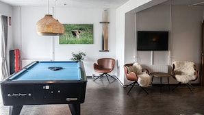 Una sala de estar moderna con mesa de billar, televisor y asientos cómodos.