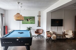 Uma sala de estar moderna com mesa de bilhar, televisão e assentos confortáveis.