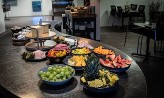 Uma mesa de buffet com diversos alimentos, incluindo frutas, legumes e carnes.