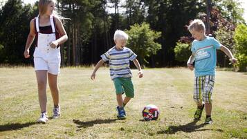 Three children playing with a soccer ball in a grassy field.