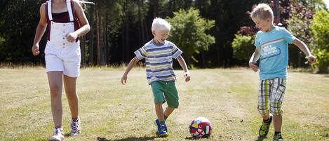Three children playing with a soccer ball in a grassy field.