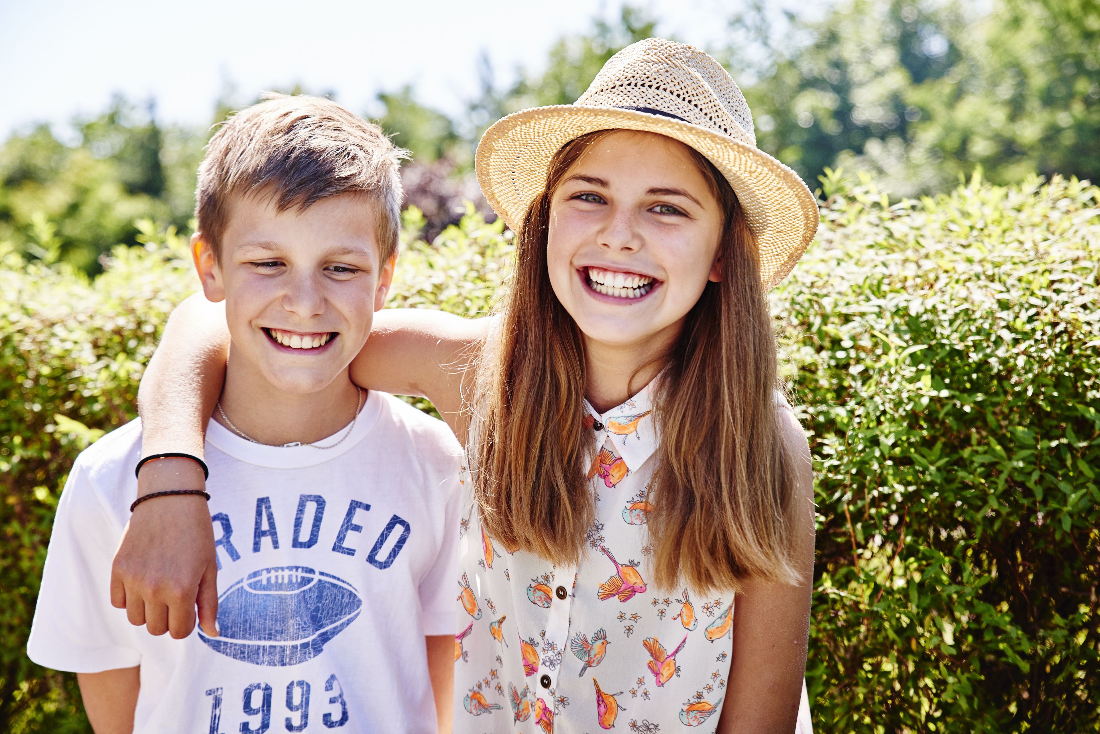 A person wearing a white t-shirt with a football and the year 1993, and another person in a floral patterned shirt and a straw hat.