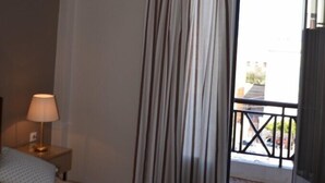 Une chambre d’hôtel avec un lit, une table de chevet avec une lampe, une fenêtre avec des rideaux et une vue sur l’extérieur.