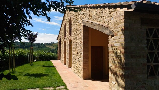 A stone building with a paved pathway leading to an arched entrance. - Capanna 1826 (San Gimignano)