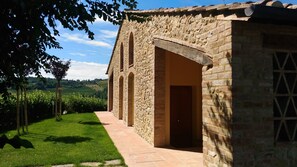 A stone building with a paved pathway leading to an arched entrance. - Capanna 1826 (San Gimignano)