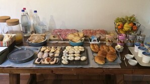 A buffet table with various food items, including pastries, bread, and fruits. - Capanna 1826 (San Gimignano)