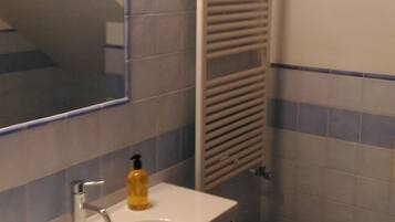A bathroom with a sink, bidet, and a towel rack.