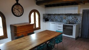 A kitchen with white cabinets, a wooden table, and a clock on the wall. - Capanna 1826 (San Gimignano)