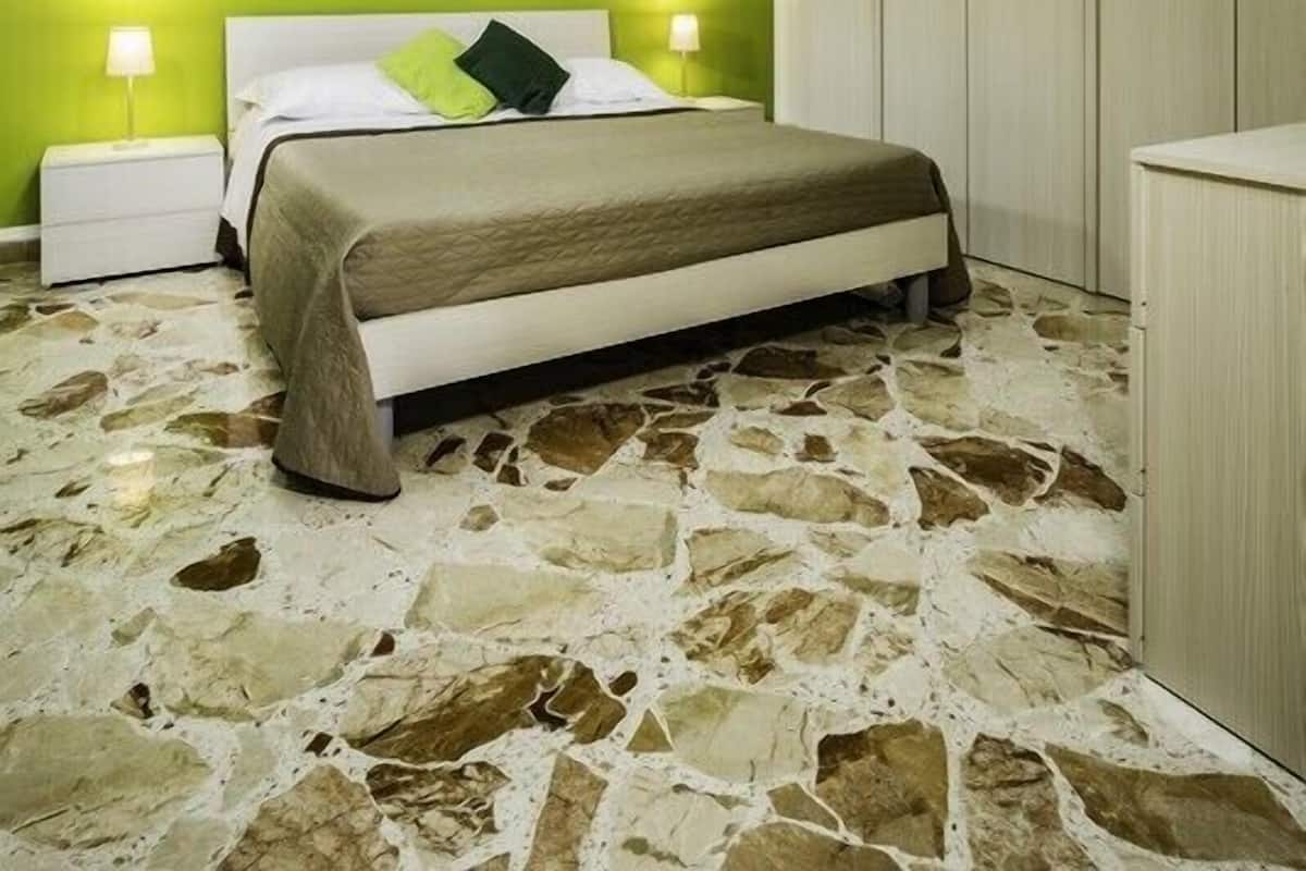 Ein Schlafzimmer mit einem Bett, zwei Nachttischen, einer grünen Wand, einem Gemälde, einem Kleiderschrank und einem Boden mit Steinmuster.