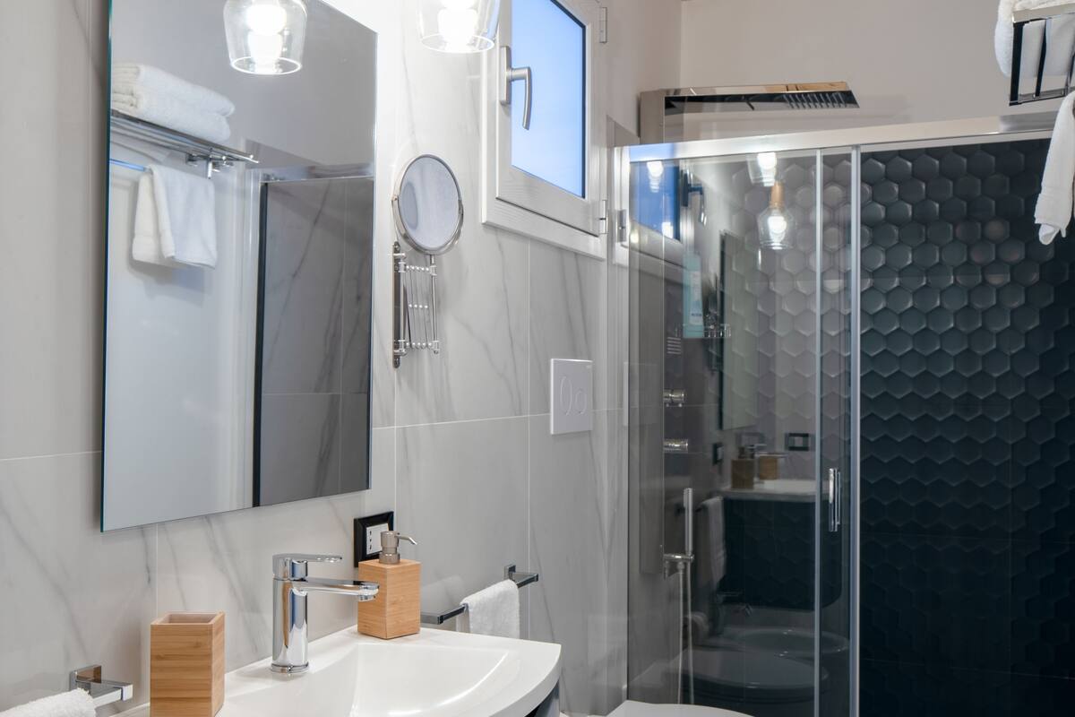 Ein modernes Badezimmer mit großem Spiegel, Waschbecken, Toilette und Duschkabine.