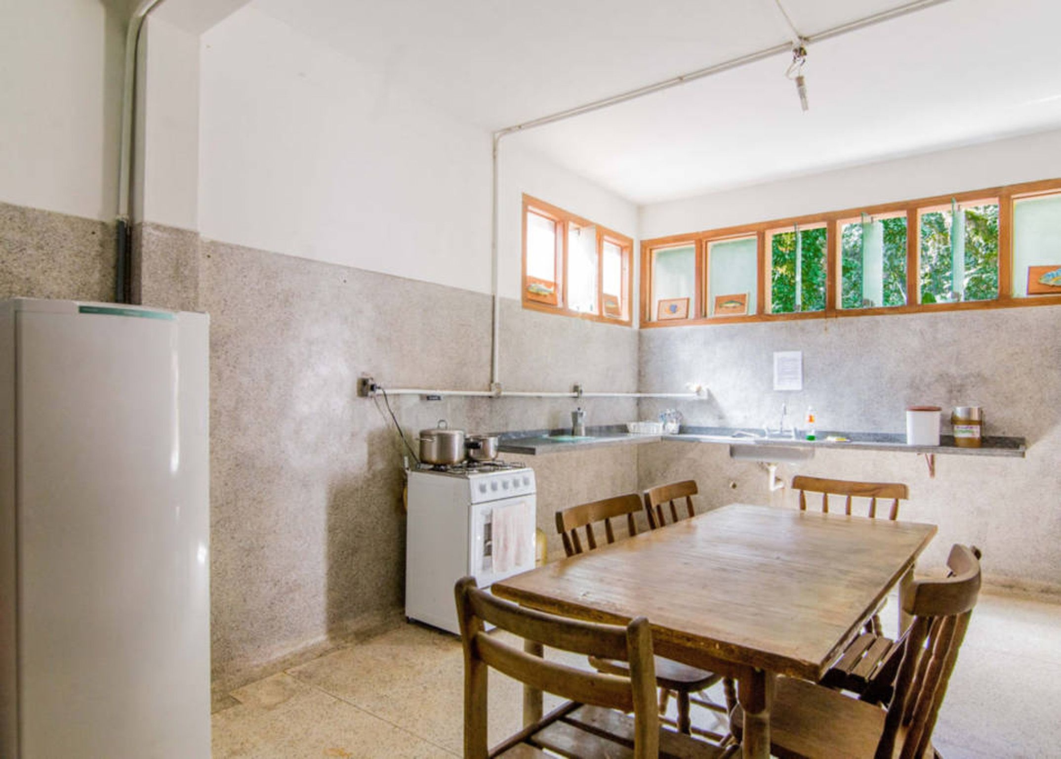 A compact kitchen with a stove, sink, and refrigerator. There is a wooden dining table with chairs.