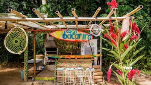 A rustic outdoor cafe named 'casa bacarino' with a bamboo structure, outdoor seating, and a small counter. - Casa Bacarirá (São Sebastião)