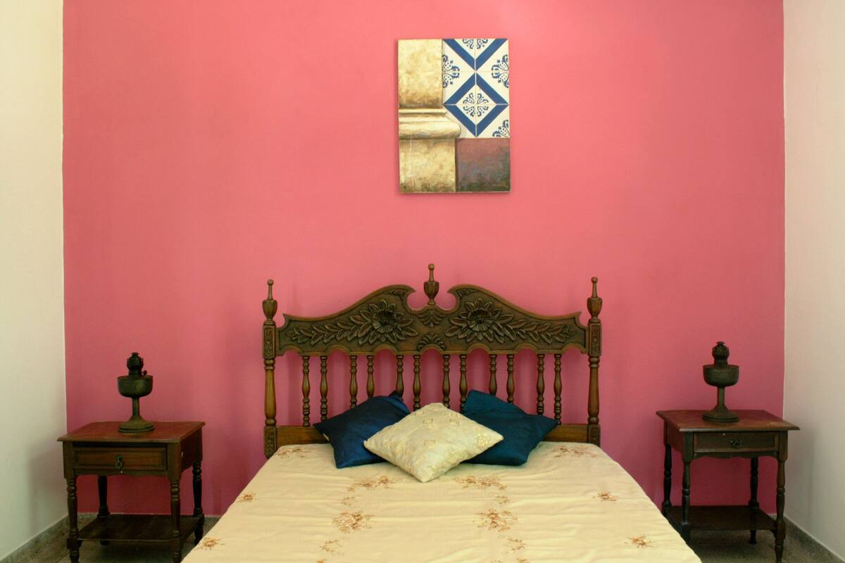 A bedroom with a wooden bed, two nightstands, and a pink wall.