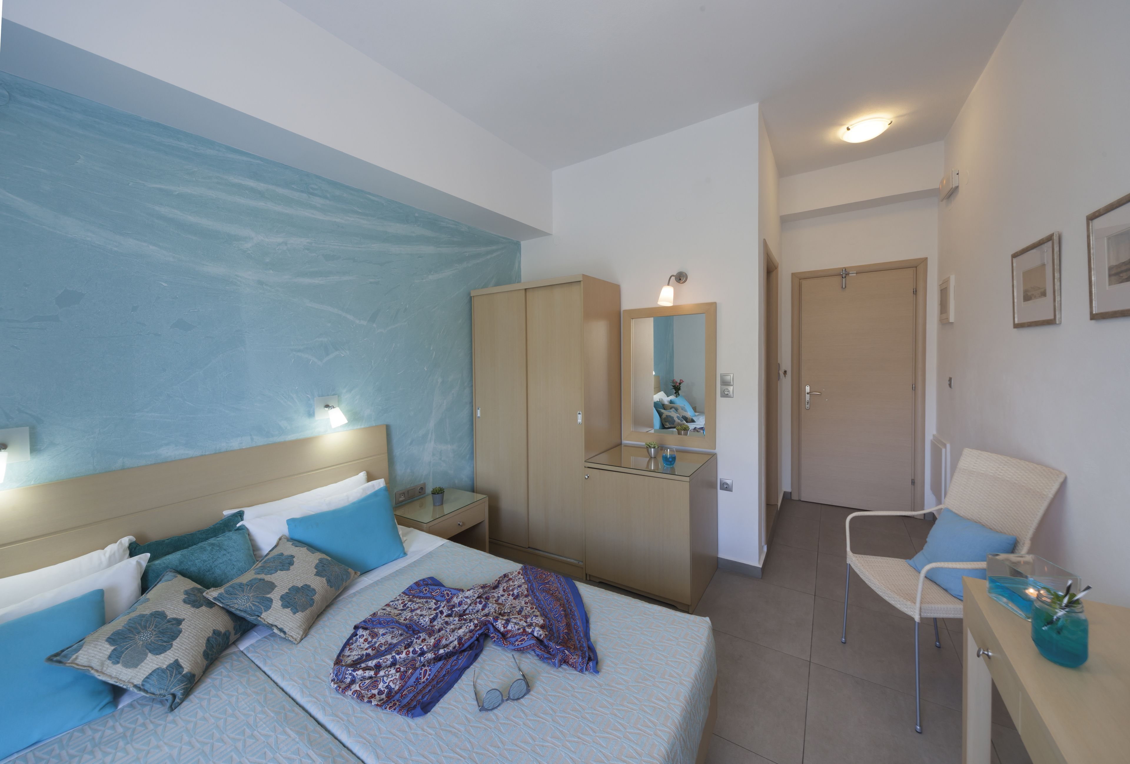 A bedroom with a bed, a wardrobe, a mirror, a chair, and a desk.