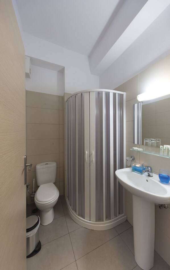 A modern bathroom with a toilet, a shower, and a sink. - Blue Harmony Hotel (Syros)