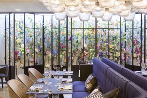 Un ristorante con un divano blu, tavoli da pranzo e un pannello decorato con motivi floreali.